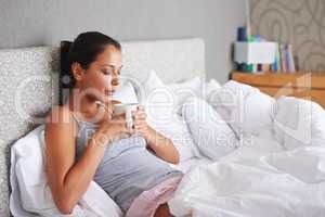 Theres nothing like a cup of coffee in the morning. Attractive young woman blowing the hot steam off her morning coffee.