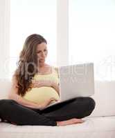 Browsing for pregnancy tips. Shot of a young pregnant woman working on her laptop at home.