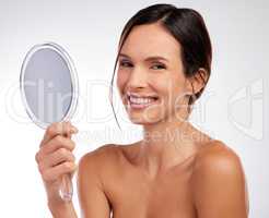 Guess what Its no blemish day. Shot of an attractive young woman holding a hand mirror and posing in the studio.