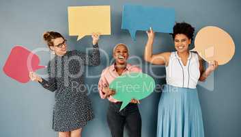 Were all for humour and fun. Studio shot of a group of attractive young businesswomen holding speech bubbles while standing against a grey background.