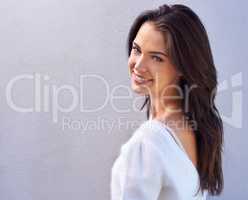 The symmetry of sweet and sensual. Portrait of a happy young woman standing against a gray background.