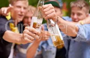 Let the good times flow. Cropped shot a group of young men toasting with beer bottles.