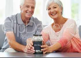 Look how far weve come. Shot of a senior couple proudly posing with their savings jar.