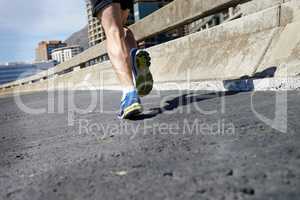 Taming the road. Cropped image of a runners legs as he runs onwards.