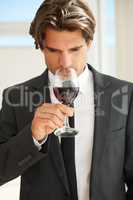 Fruity yet playful. A handsome wine connoisseur enjoying a glass of red wine.