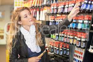 Looking for that perfect color. Shot of a young female artist shopping for acrylic paint in an art store for supplies.