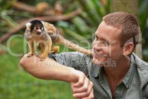 Tarzan loved spending time with his little friend. Shot of a young man interacting with a little monkey at a wildlife park.