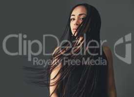 Braids in the breeze. Studio portrait of a beautiful young woman posing against a gray background.