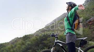 I feel so free. A pretty young woman mountain biking in a scenic setting.