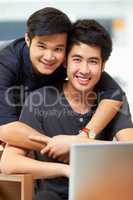 Content just to be together. Portrait of an affectionate young gay couple relaxing at home with a laptop.
