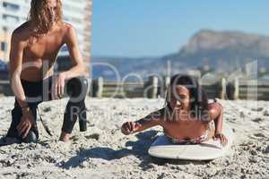 Its harder than it seems. Shot of young woman getting surfing lessons from a young man.