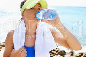 Staying hydrated. An attractive and athletic young woman drinking water after a run.