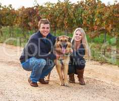 Hes a member of their family. Portrait of a young couple with their pet Alsatian on a wine farm.