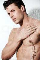 Dripping with masculinity. Cropped shot of a muscular young man under the running water of a shower.