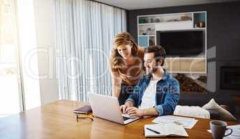 We always work as a team. Shot of a young couple doing some financial planning together on a laptop at home.