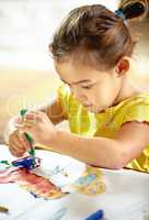 Getting creative with color. Shot of an adorable little girl making a mess while painting.
