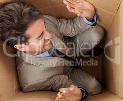 Trapped in his career. Concept shot of a young businessman trapped in a cardboard box.