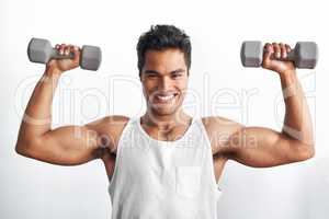 Building a beautiful body. Studio portrait of an athletic young man holding up dumbbells.