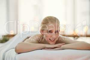 So glad I decided to make today a spa day. Portrait of a young woman relaxing on a massage table at a spa.