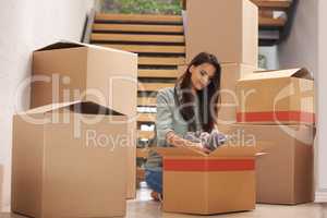 Moving on to greener pastures. Young woman packing up boxes in an apartment.