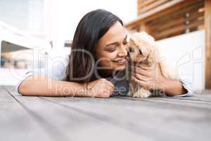 Pets dont see imperfections, only love. Shot of a young woman relaxing with her dog on a wooden porch outdoors.