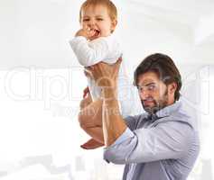 It can be a dirty job sometimes.... Shot of a handsome father holding his son up in the air while making a face.