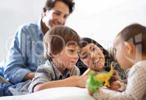 Big brother bonding. Shot of a happy brother and sister playing with their toys while their parents look on.