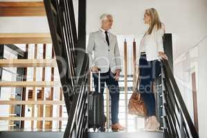 The place looks great so far. Shot of two confident businesspeople walking down stairs together while talking inside a building during the day.