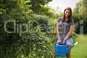 Keeping her garden lush. Cropped shot woman watering flowers in her garden.