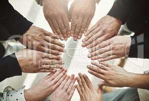 What a unique way of building team spirit. Shot of a group of unrecognizable businesspeoples hands forming a huddle together inside of the office.