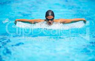 Bettering her time stroke by stroke. A focused young female swimmer doing the butterfly stroke.