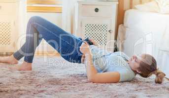 The struggle is real. Shot of a young woman struggling to fit into her jeans at home.
