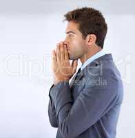 Praying for that promotion. Profile of a businessman standing with palms together and rested against his mouth in gesture of anticipation.