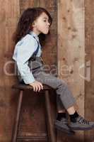 I like my style old-school. Shot of a cute little boy in old-fashioned overalls sitting on a stool.