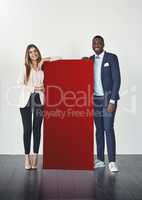 With this color, everyones going to notice your message. Studio shot of a young businessman and businesswoman standing next to a blank red placard.