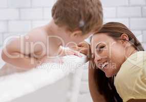 Making sure her baby boy is fresh and clean. An infant boy washing in the bath under his mothers supervision.