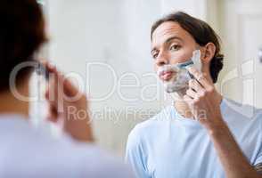 Take your time to prevent accidents. Shot of a young man shaving his face in the morning.