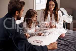 Boredom has no place in this house. Shot of a young family playing cards together at home.