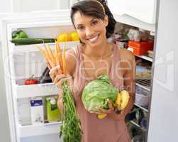 Only the most healthy ingredients for me. Portrait a young woman holding fresh produce in a kitchen.