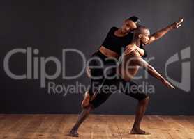 Balance of male and female energies. A female and male contemporary dancer performing a dramatic pose in front of a dark background.