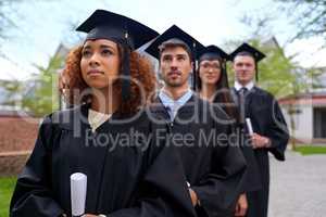 Higher education for high aspirations. Shot of graduating university students standing in a row looking up.