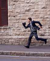 Im late. Shot of a young businessman running down a street.