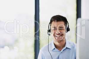 Creating an effortless customer service experience. Portrait of a happy young man wearing a headset and using a computer at work.