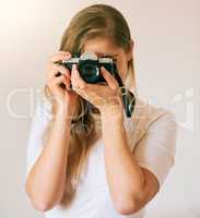 Freezing this moment in time. Shot of an unrecognizable young woman taking a photo with her camera at home.