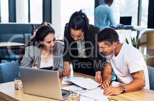 Theyre always thorough about their plans. Shot of a group of businesspeople going through paperwork together in an office.