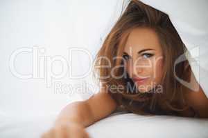 Natural seduction. Portrait of a gorgeous brunette in bed under the covers.