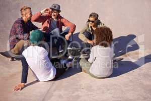 Good times with friends. Shot of a group of friends sitting in the sun at a skate park.