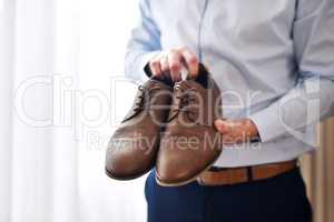 Taking my first steps as a married man in these. Shot of an unrecognizable bridegroom holding the shoes hes going to wear inside a dressing room on his wedding day.