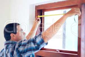 The exact measurement. Shot of a middle aged handy man measuring a window.