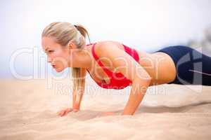 Whole body health. Shot of a young woman in sportswear doing pushups on the beach.